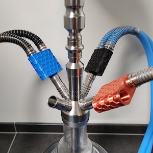 Könnte beinhalten: Eine Edelstahl-Shisha mit drei Schläuchen. Die Schläuche haben unterschiedlich farbige Silikonmundstücke: blau, schwarz und orange. Die Mundstücke haben ein Wabenmuster.