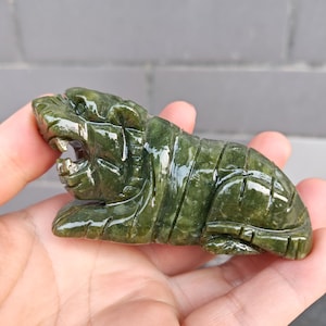 Pode incluir: Uma escultura de jade verde de um tigre, com detalhes intrincados e um acabamento brilhante.