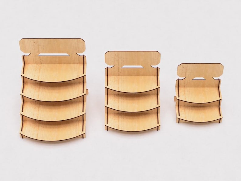 May include: Three wooden display stands with three shelves each. The stands are different sizes, with the largest stand on the left and the smallest stand on the right. The stands are made of light brown wood and have a simple design.