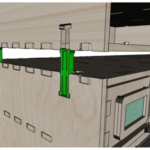 May include: A close-up of a wooden cabinet with two green plastic clips holding the top and bottom sections together. The cabinet has a series of small rectangular openings on the front.