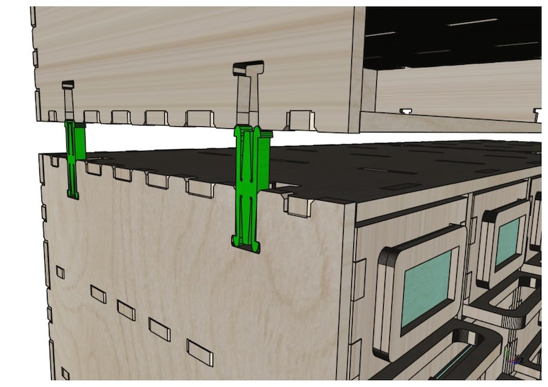 May include: A close-up of a wooden cabinet with two green plastic clips holding the top and bottom sections together. The cabinet has a series of small rectangular openings on the front.