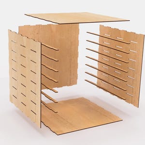 May include: A disassembled wooden cube with a grid pattern on each side. The cube is made of light brown wood and has a natural finish.