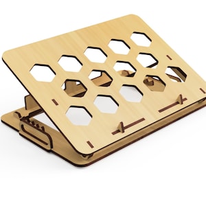 Pode incluir: Um suporte para laptop de madeira com um design de favo de mel. O suporte est&aacute; dobrado e tem uma cor marrom claro.