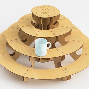 May include: A light wood-colored, tiered display stand with a circular design. The stand has three levels, each with a curved shape, and a small, light blue mug is placed on the middle tier. The stand is made of wood and has a modern design.