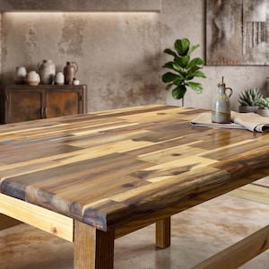 May include: A large, rectangular wooden table with a patchwork design. The table is made of various shades of brown wood and has a natural finish. A small ceramic bottle and a linen cloth sit on the table. The table is approximately 72 inches long.