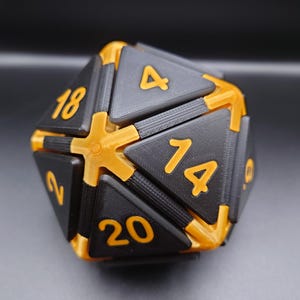 May include: A black and gold twenty-sided die, numbered 1 to 20. The die features black triangular faces with gold numerals and gold connectors. This die is designed for use in tabletop role-playing games.