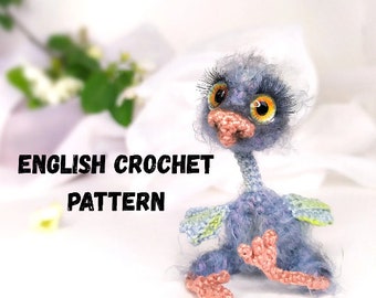 May include: Crocheted amigurumi ostrich toy with blue and green feathers, pink feet, and large orange eyes. The toy is sitting on a white surface with the text "ENGLISH CROCHET PATTERN" in black.