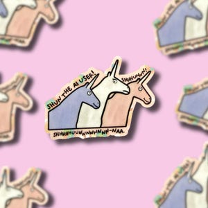 May include: A sticker featuring three cartoon unicorns in blue, white, and tan. The text reads SHUN THE AI USER! and SHHHHUNNN! SHHHHHHUUNNNNNNNNN-NAA. The unicorns have simple black outlines and expressive eyes on a light pink background.