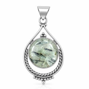 May include: A silver pendant featuring a round, translucent stone with dark, needle-like inclusions. The stone is set within a circular frame accented with twisted rope detailing and small silver beads at the top and bottom, topped by a triangular bail.