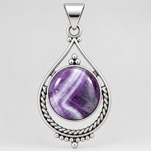 May include: A silver pendant featuring a round, polished purple and white chevron amethyst stone set within a teardrop-shaped frame. The frame includes twisted rope detailing on the sides, small decorative spheres, and a triangular bail at the top.