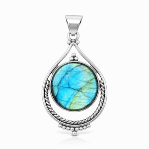 May include: A silver pendant featuring a round, iridescent labradorite gemstone with blue and green flashes. The stone is encased in a circular frame with a twisted rope texture, accented by small silver beads at the top and bottom, and a bail.