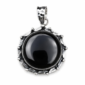 May include: A round pendant featuring a smooth, polished black stone set in a textured, oxidized silver frame. The metal border has a hammered, rustic finish with small bead accents along the edge and a matching hammered bail at the top.