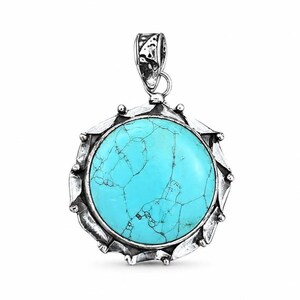 May include: A round pendant featuring a bright turquoise stone with dark veining, set in a textured, oxidized silver frame with a scalloped edge and a decorative bail at the top. The metalwork has a dark, weathered finish that contrasts with the stone.
