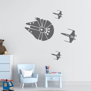 May include: A gray wall decal featuring the Millennium Falcon and three X-wing starfighters from Star Wars. The decal is applied to a white wall in a child's room.