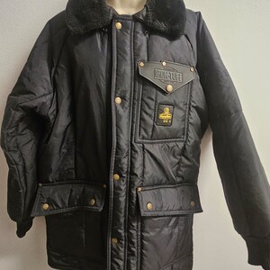 May include: Black quilted jacket with a faux fur collar and a patch on the left chest that reads "Iron-Tuff" in gold lettering.