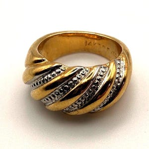 Può includere: Un anello bicolore caratterizzato da fasce diagonali alternate in oro giallo lucido e metallo argentato testurizzato. L'interno della fascia è stampato con il testo 14K, che indica il contenuto d'oro di questo gioiello largo e bombato.