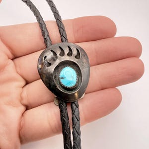 Può includere: Una tazza di ceramica bianca con manico nero e la scritta "But First, Coffee" in stile scritto a mano. La tazza è su una superficie bianca. La tazza è alta circa 10 cm.