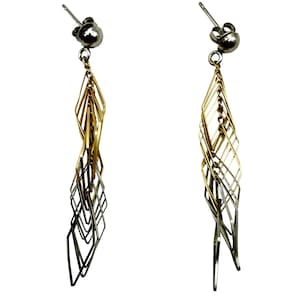 May include: A pair of dangling earrings with a silver post and a spiral design. The earrings feature a combination of gold and silver tones, with a geometric, openwork pattern. The earrings are designed to hang down from the ear.