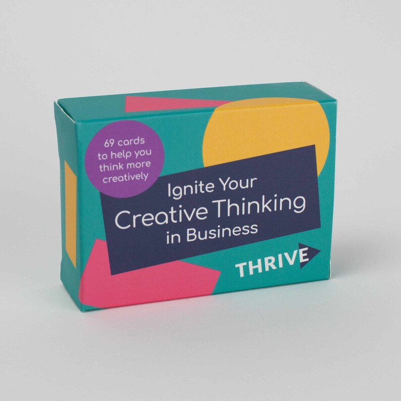 Może przedstawiać: Turkusowe pudełko z r&oacute;żowym, ż&oacute;łtym i niebieskim wzorem. Pudełko zawiera 69 kart, kt&oacute;re pomogą Ci myśleć bardziej kreatywnie. Tekst na pudełku brzmi "Ignite Your Creative Thinking in Business" i "THRIVE".