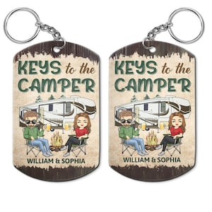 May include: A pair of wooden keychains with a rustic design. Each keychain features a cartoon couple sitting by a campfire in front of a camper van. The text "KEYS to the CAMPER" is printed on each keychain. The names "WILLIAM & SOPHIA" are printed on the bottom of each keychain.