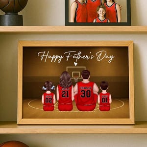 May include: A framed print with a basketball theme. The image features a family of four in red basketball jerseys, with the text "Happy Father's Day" above them. The jerseys have names and numbers. A family photo is above the framed print.