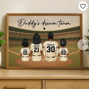 May include: A framed print featuring a family of four in baseball uniforms, facing away from the viewer. The text "Daddy's dream team" is above them. The baseball field and stadium are in the background. The family members are wearing baseball caps.