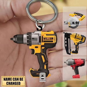 May include: A yellow and black power drill keychain featuring the name WILLIAM printed on the side. The keychain includes a silver metal ring. Additional tool-shaped keychain designs are shown in smaller panels on the right side of the image.