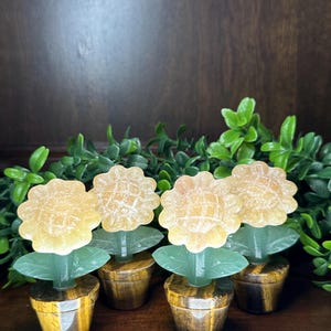 May include: Four small, carved flower sculptures made of citrine and green aventurine. Each flower is in a tiger's eye pot.