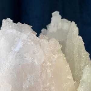 May include: A cluster of translucent white crystalline structures with jagged, sharp edges and a rough, textured surface. The mineral formation displays varying degrees of opacity, ranging from clear, glass-like points to milky, opaque sections.