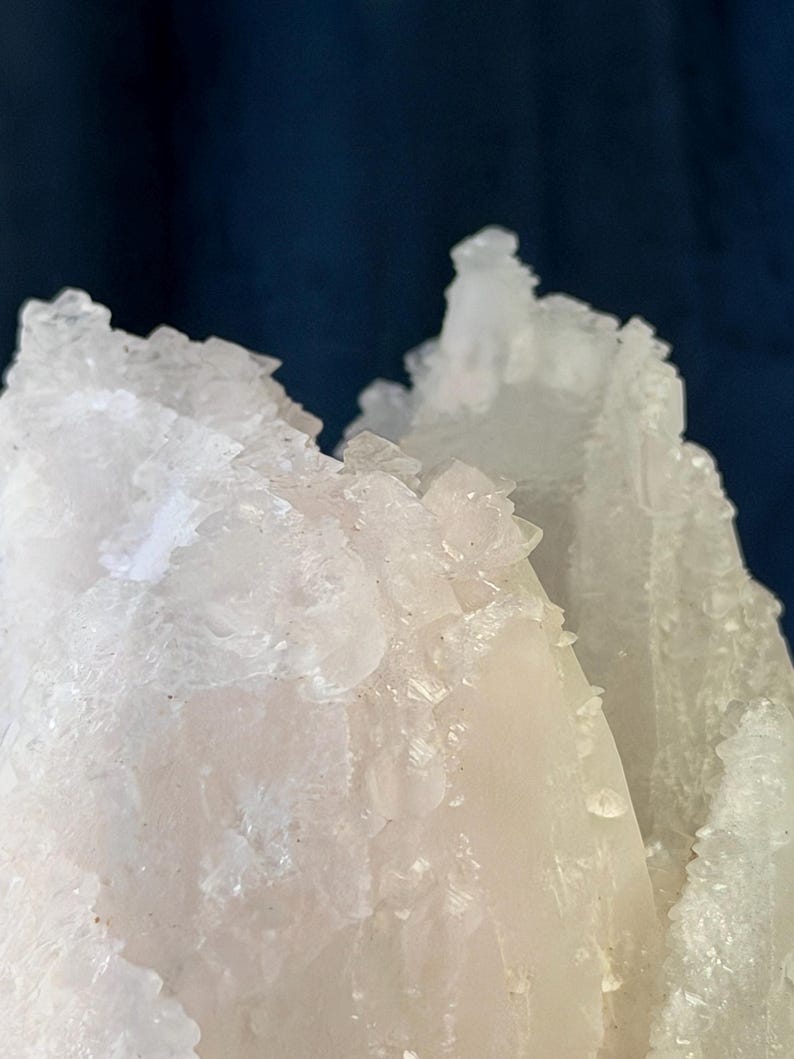 May include: A cluster of translucent white crystalline structures with jagged, sharp edges and a rough, textured surface. The mineral formation displays varying degrees of opacity, ranging from clear, glass-like points to milky, opaque sections.