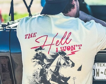 May include: A light beige t-shirt with a black and white illustration of a cowboy riding a horse. The text "THE Hell I WON'T" is printed in red on the shirt.