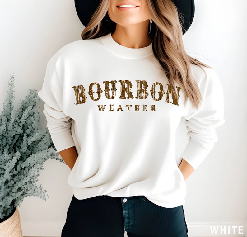 May include: White sweatshirt with brown text that reads "Bourbon Weather".