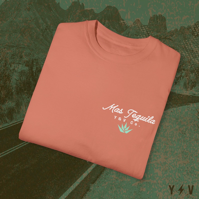 May include: A coral coloured t-shirt with a white logo that says "Mas Tequila Y&V Co." with a green agave plant graphic.