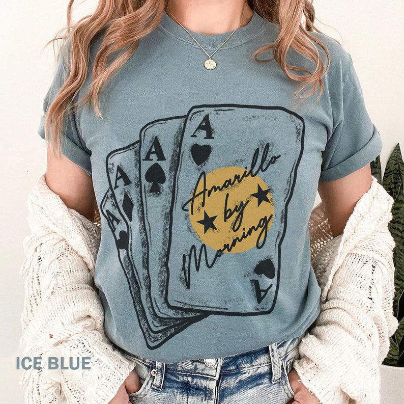 May include: A blue t-shirt with a graphic of four playing cards with the text "Amarillo by Morning" in a circle with stars.