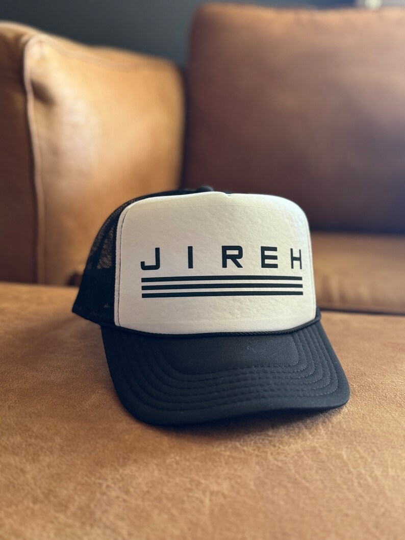 May include: A black and white trucker hat with the word "JIREH" in black letters on the front. The hat has a black mesh back and a white front panel.