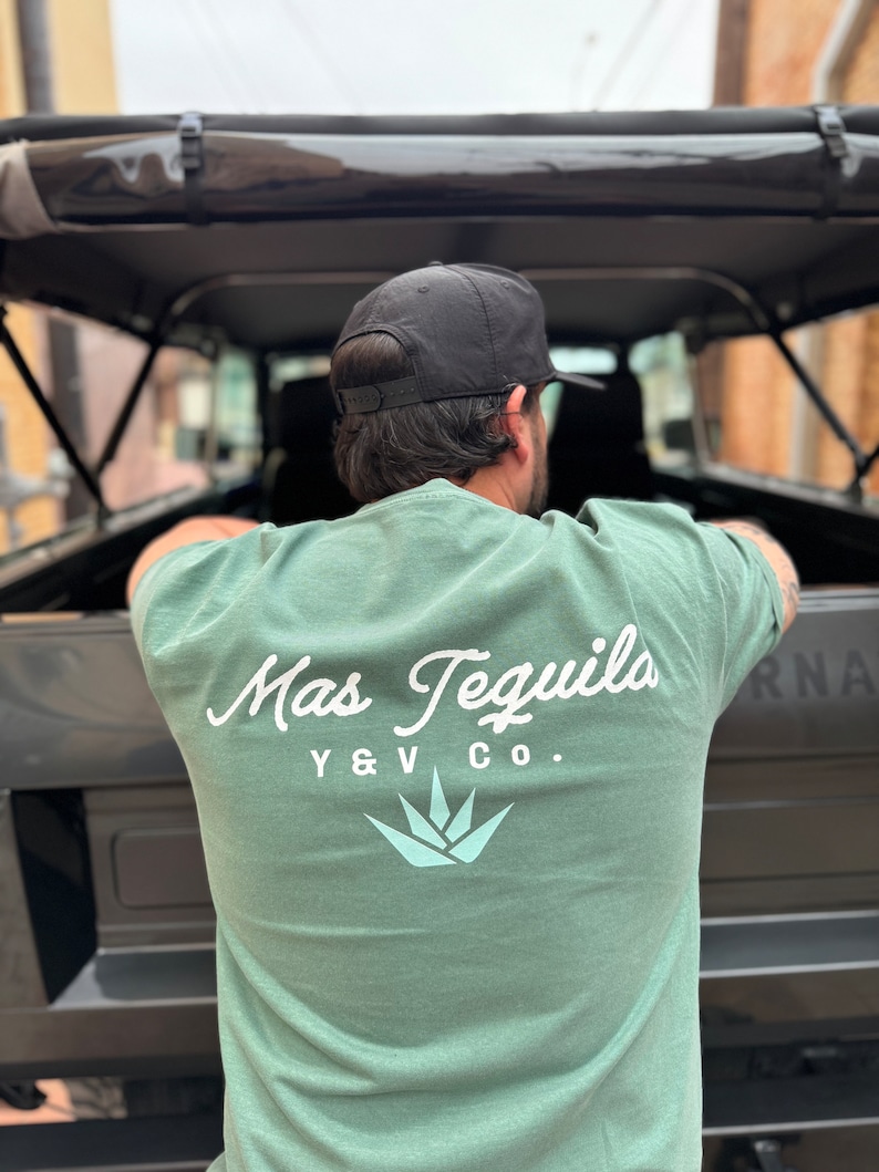 May include: A sage green t-shirt with a white graphic of a stylized agave plant and the text "Mas Tequila Y & V Co."