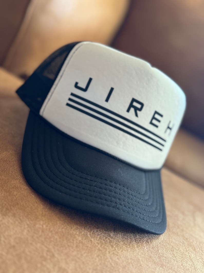 May include: A black and white trucker hat with the word "JIREH" printed in black on the front. The hat has a black mesh back and a white front.