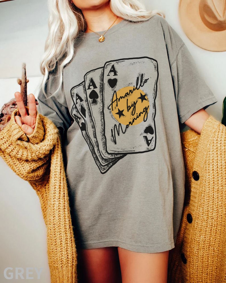 May include: A grey t-shirt with a graphic of four playing cards with the text "Amarillo by Morning" on the front.