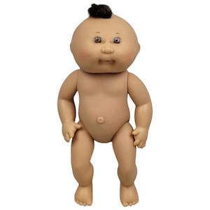 May include: A Cabbage Patch Kid doll with a brown mohawk, brown eyes, and rosy cheeks. The doll is nude and standing with its legs slightly apart.