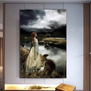 May include: A woman in a long, flowing dress stands by a still lake, looking out at a cloudy sky. A white bird stands beside her.