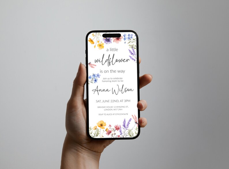 Puede incluir: Una invitaci&oacute;n digital para un baby shower con un borde floral de acuarela. El texto dice "una peque&ntilde;a flor silvestre est&aacute; en camino" y "Anna Wilson". La invitaci&oacute;n incluye la fecha, la hora y la ubicaci&oacute;n del baby shower.