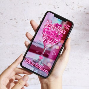 Op de afbeelding: Een smartphone toont een roze afbeelding voor Galentine's Girls Night, met een martini glas ontwerp, harten en de tekst "Galentine's Girls Night" en "Elisa Wilson".