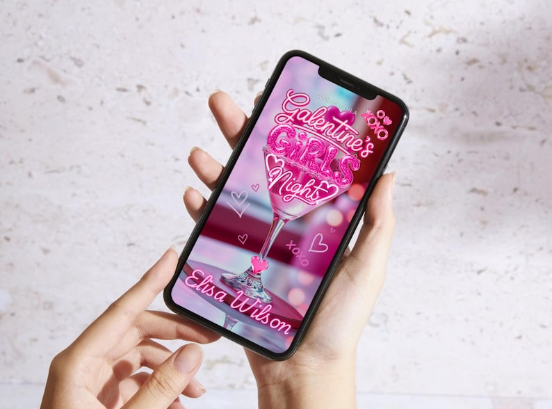 Op de afbeelding: Een smartphone toont een roze afbeelding voor Galentine's Girls Night, met een martini glas ontwerp, harten en de tekst "Galentine's Girls Night" en "Elisa Wilson".