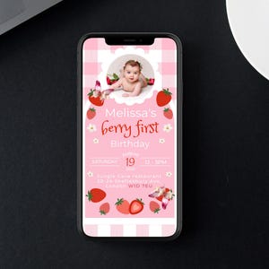 May include: A pink digital invitation on a smartphone screen. The invitation features a baby's photo, strawberries, and the text "Melissa's berry first Birthday." The date and time are also included. The background has a pink gingham pattern.