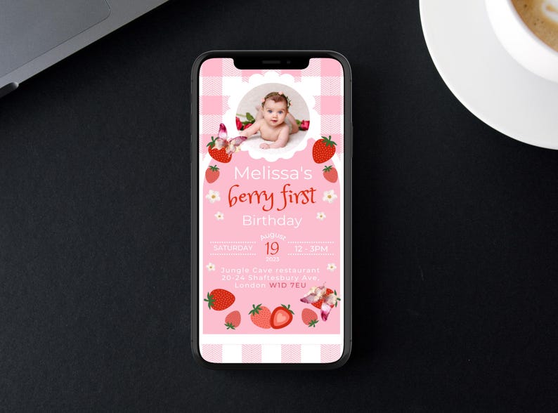 May include: A pink digital invitation on a smartphone screen. The invitation features a baby's photo, strawberries, and the text "Melissa's berry first Birthday." The date and time are also included. The background has a pink gingham pattern.