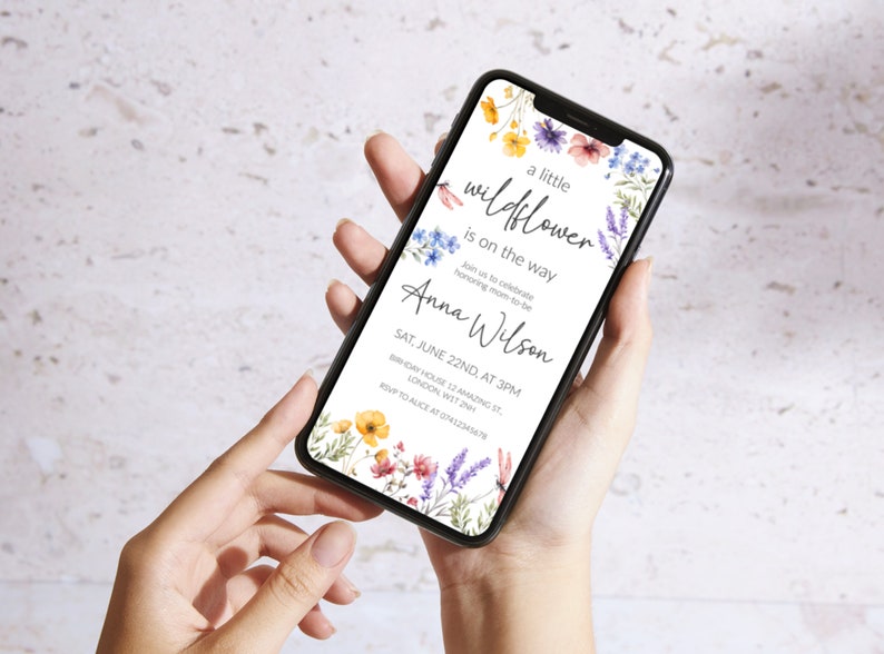 Puede incluir: Una invitaci&oacute;n digital con un dise&ntilde;o floral que presenta una ilustraci&oacute;n de acuarela de flores silvestres en tonos azules, amarillos, rosas y morados. El texto dice "a little wildflower is on the way" e incluye el nombre "Anna Wilson" y los detalles de un baby shower el 22 de junio a las 3 pm.