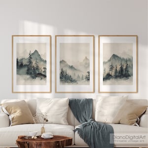 Könnte beinhalten: Ein Set aus drei gerahmten Aquarelldrucken mit einer nebeligen Berglandschaft und einem Wald aus dunkelgrünen Bäumen. Die Drucke sind im minimalistischen Stil gehalten und haben eine gedeckte Farbpalette.