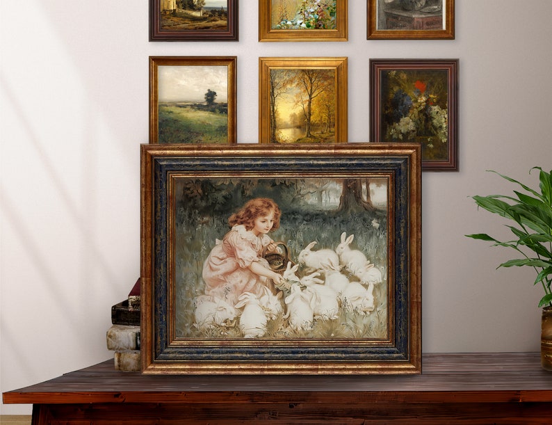 May include: A framed painting of a young girl in a pink dress feeding a group of white rabbits in a forest setting.