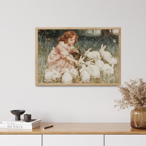 May include: A young girl in a pink dress feeds a group of white rabbits in a garden setting. The girl is holding a basket and the rabbits are gathered around her.