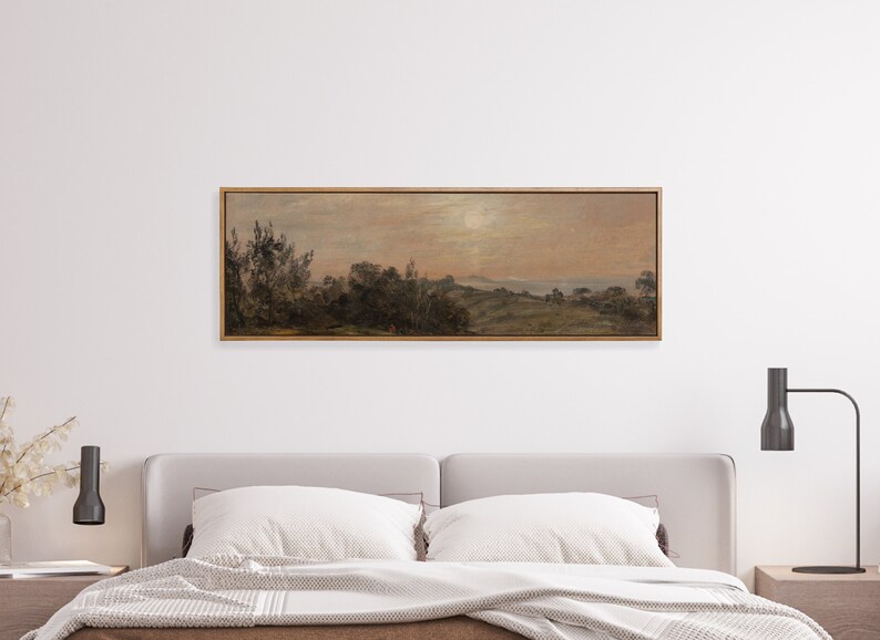 May include: A framed landscape painting depicting a rural scene with trees, hills, and a body of water in the distance. The sky is a soft pink and orange, suggesting a sunset or sunrise.